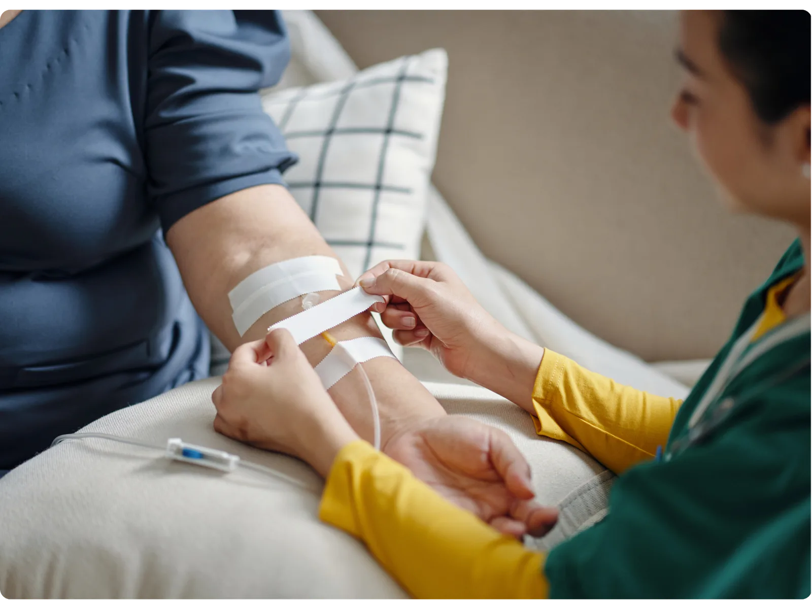 A nurse placing an IV line for a patient receiving infusion therapy at home